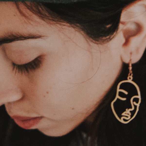 A girl wearing a 3D printed earring made from a design graphic via Silveryway ImageTo3D web app